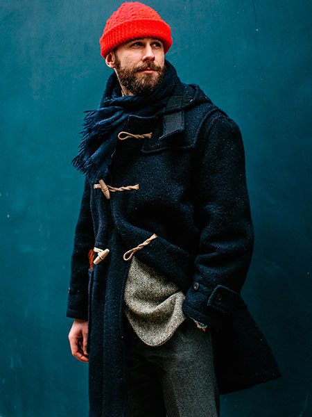 L'immagine con il dufflecoat blu scuro e una sciarpa in tono ad esso Il dufflecoat da uomo con una sciarpa ed un cappello